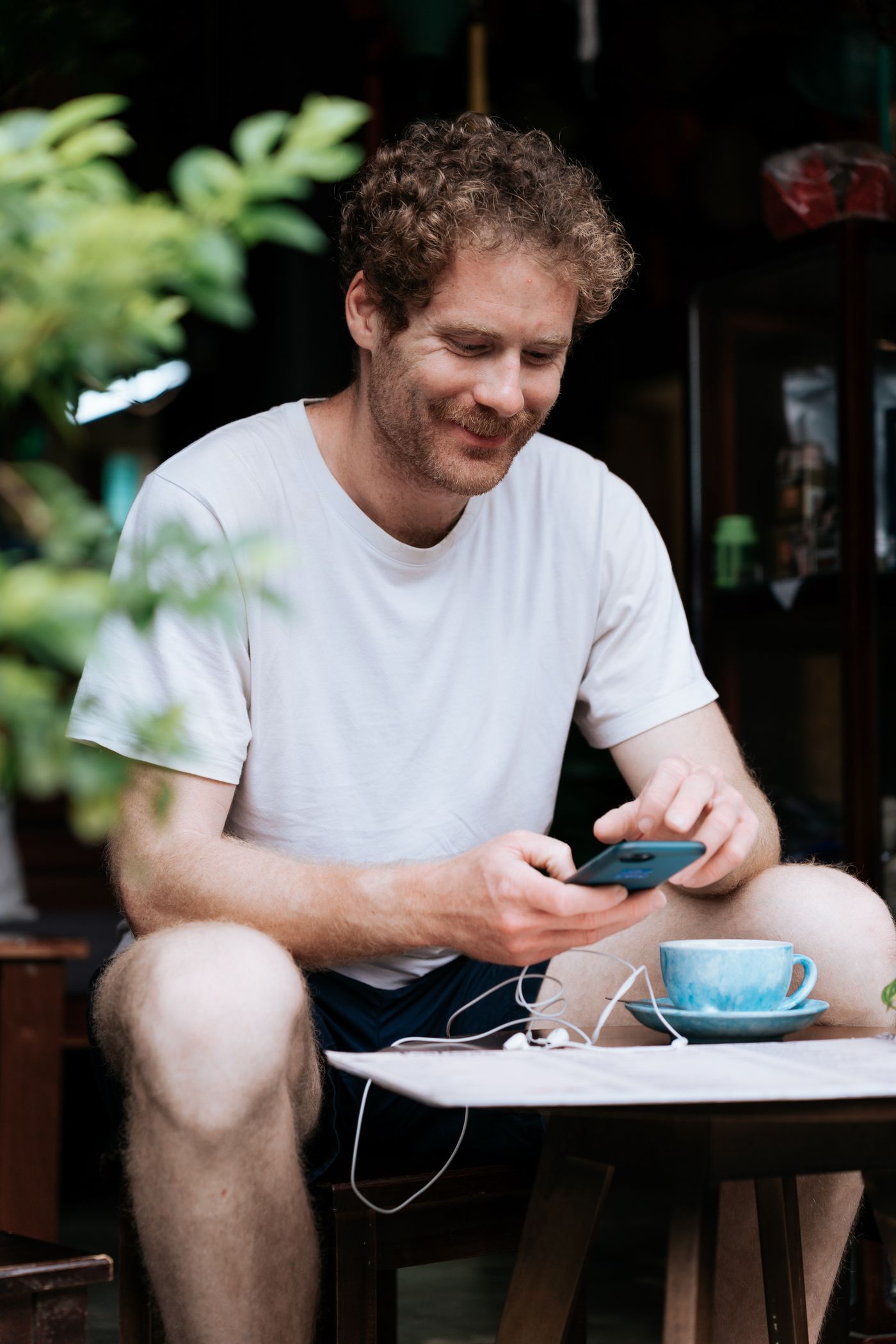 Mann nutzt in einem Café das Smartphone für die Online-Belehrung